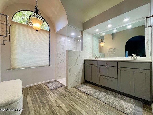 bathroom featuring hardwood / wood-style flooring, vanity, walk in shower, and tile walls