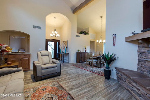 living room with light hardwood / wood-style flooring, high vaulted ceiling, a chandelier, and beamed ceiling