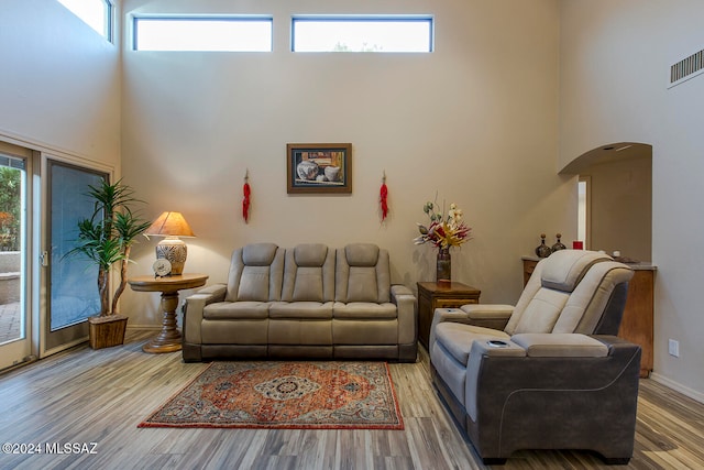 living room featuring hardwood / wood-style flooring, plenty of natural light, and a high ceiling