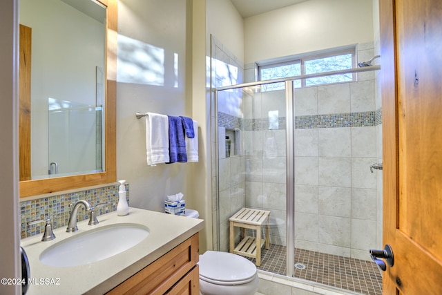 bathroom featuring decorative backsplash, toilet, a shower with door, and vanity