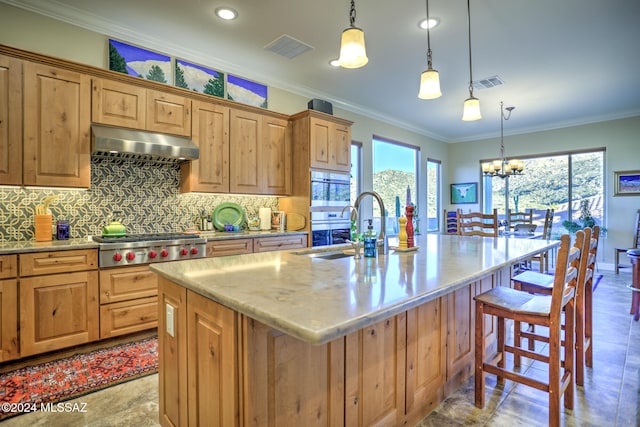 kitchen with stainless steel gas stovetop, backsplash, an inviting chandelier, an island with sink, and decorative light fixtures