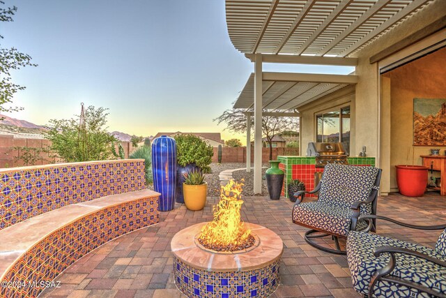 patio terrace at dusk featuring a pergola and an outdoor fire pit