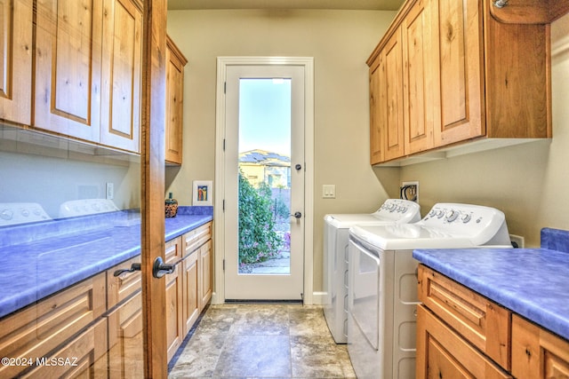 clothes washing area with separate washer and dryer and cabinets