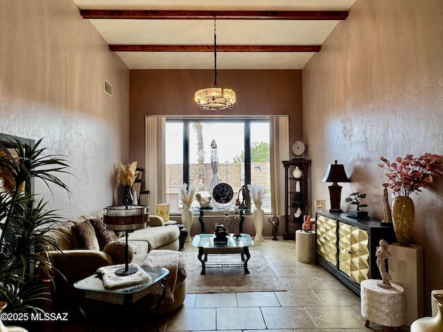 living area featuring visible vents, a textured wall, beam ceiling, and an inviting chandelier