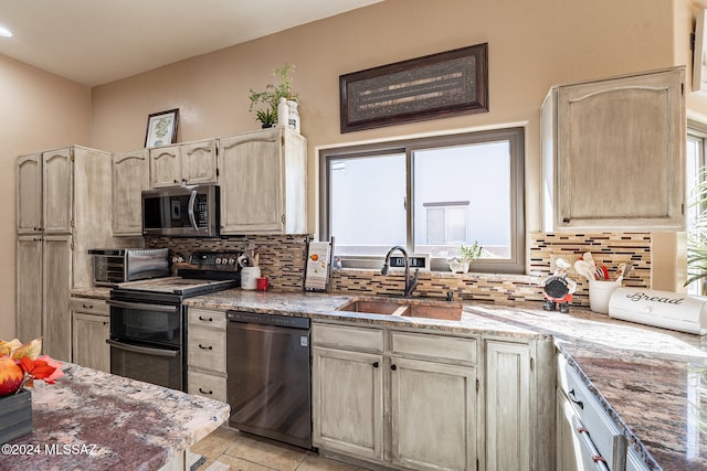 kitchen with sink, black appliances, light stone counters, and tasteful backsplash