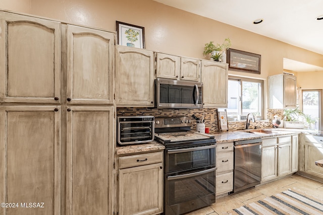 kitchen featuring light tile patterned floors, sink, backsplash, appliances with stainless steel finishes, and light brown cabinetry