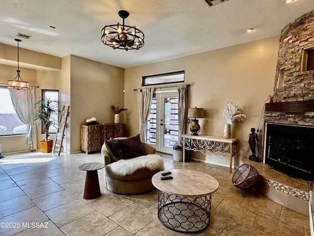 living room featuring french doors, visible vents, a stone fireplace, and a textured ceiling