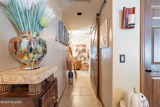 corridor with a barn door and light tile patterned flooring