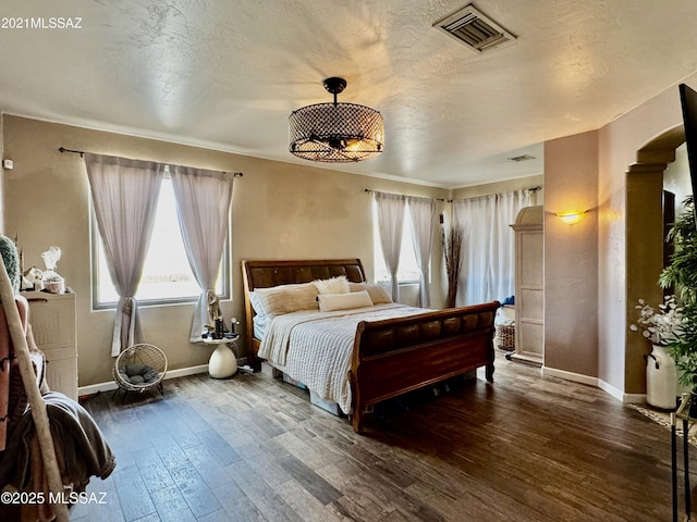 bedroom with a textured ceiling, multiple windows, visible vents, and hardwood / wood-style floors