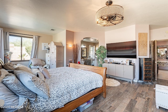 bedroom with arched walkways, visible vents, and wood finished floors