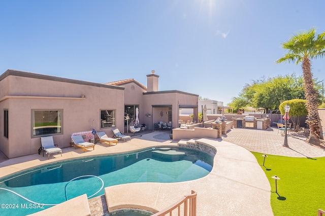 view of pool with a jacuzzi, exterior kitchen, and a patio area