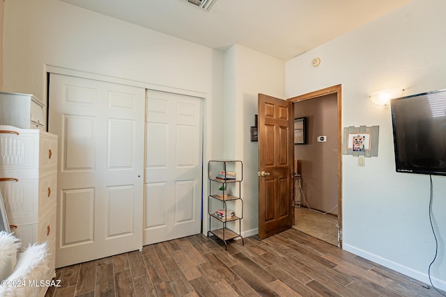 unfurnished bedroom with dark wood-type flooring, a closet, and baseboards