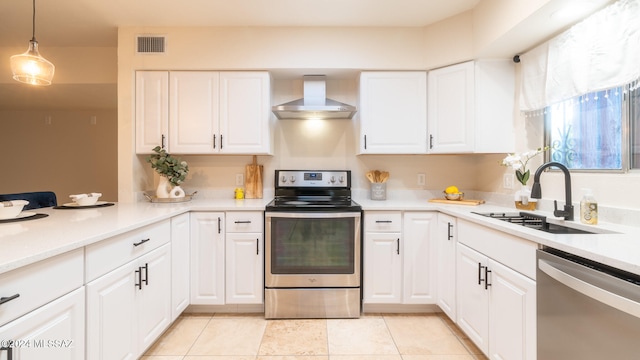 kitchen with wall chimney range hood, white cabinets, sink, and stainless steel appliances