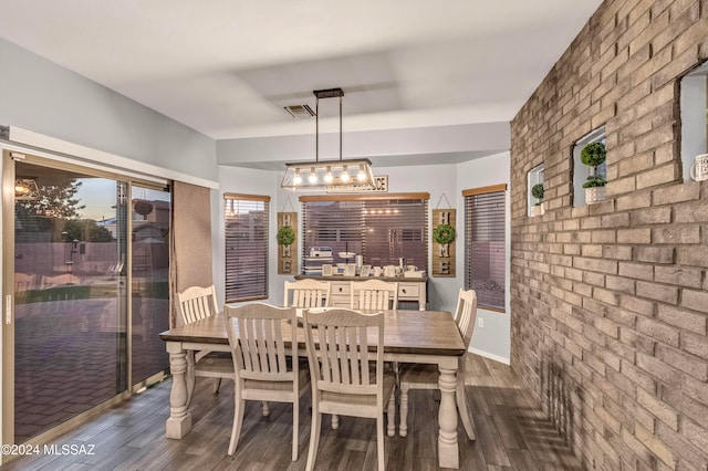 dining space with dark wood-type flooring and brick wall