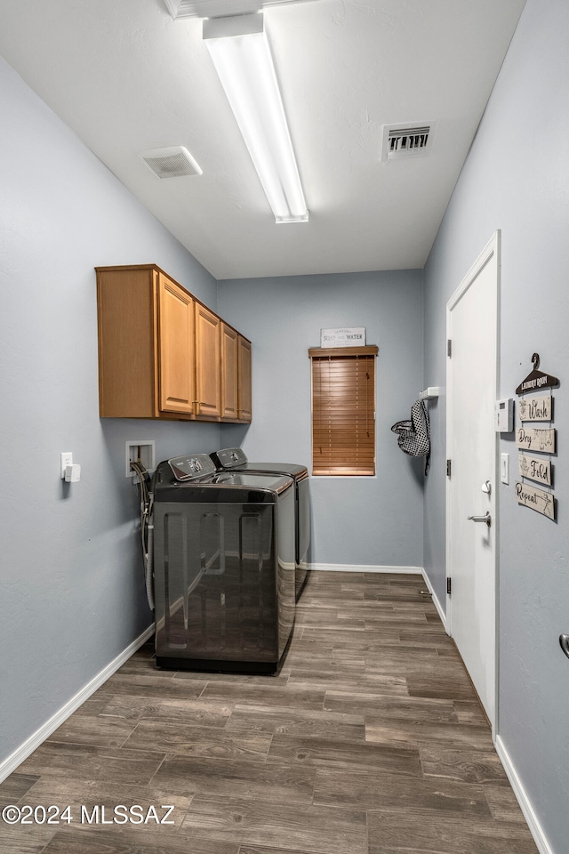 laundry room featuring cabinets, dark hardwood / wood-style floors, and washer and clothes dryer