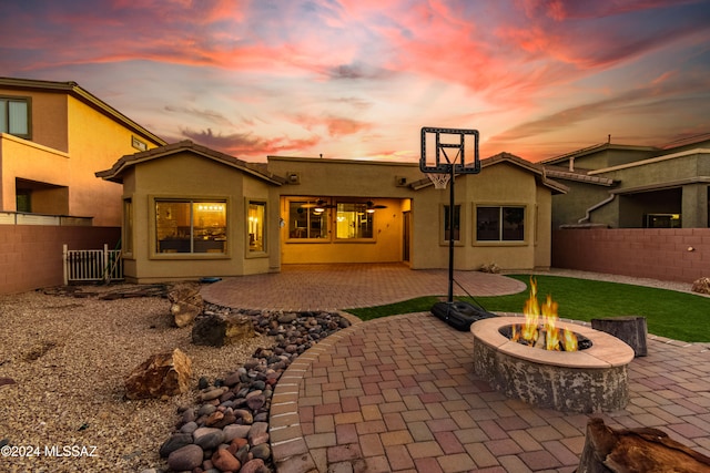 back house at dusk featuring a fire pit and a patio