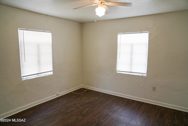 spare room with dark hardwood / wood-style flooring, a wealth of natural light, and ceiling fan