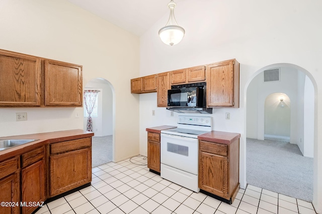 kitchen featuring decorative light fixtures, light tile patterned floors, white electric stove, sink, and a high ceiling