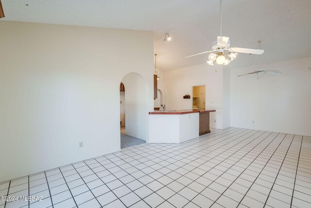 tiled spare room with high vaulted ceiling and ceiling fan