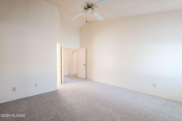 spare room with a textured ceiling, high vaulted ceiling, light colored carpet, and ceiling fan