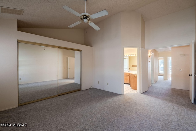 unfurnished bedroom with high vaulted ceiling, light carpet, and a closet