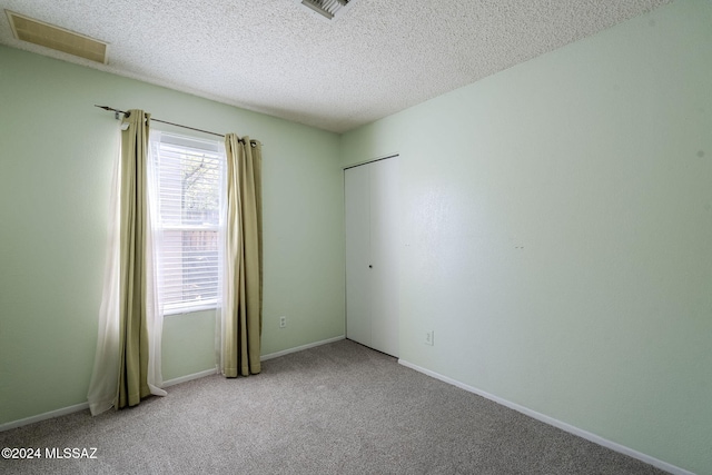 empty room featuring light colored carpet and a textured ceiling