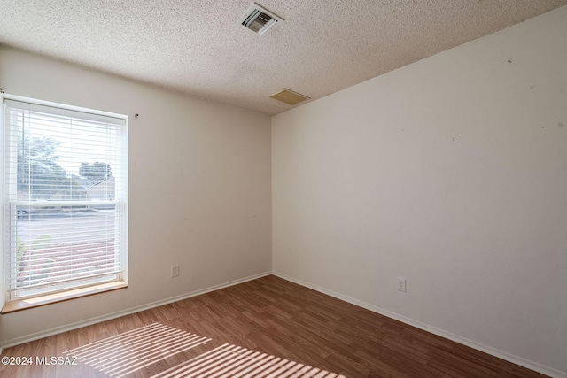 empty room with wood-type flooring and a textured ceiling