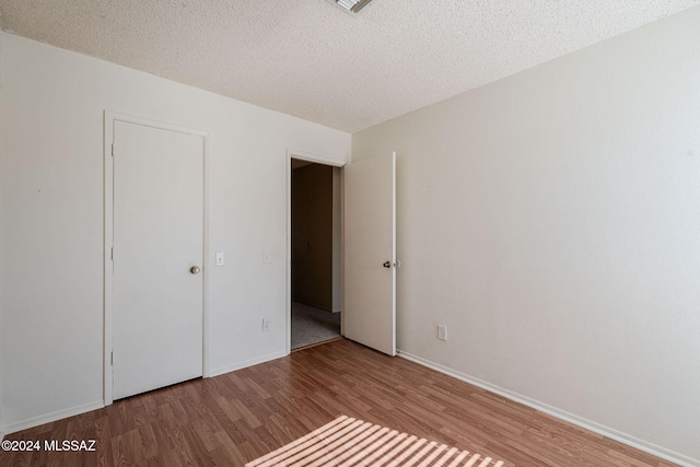 unfurnished bedroom with hardwood / wood-style floors and a textured ceiling