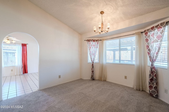 empty room with a textured ceiling, lofted ceiling, ceiling fan with notable chandelier, and carpet floors