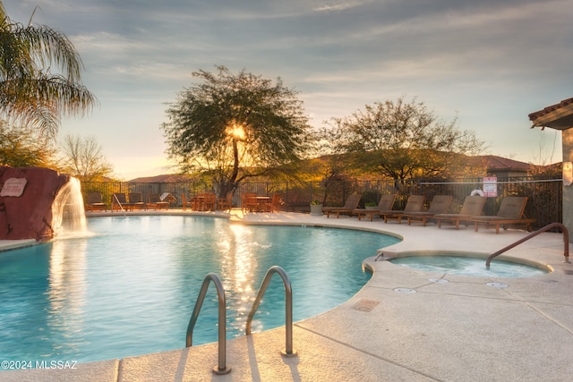 pool at dusk with a patio and pool water feature