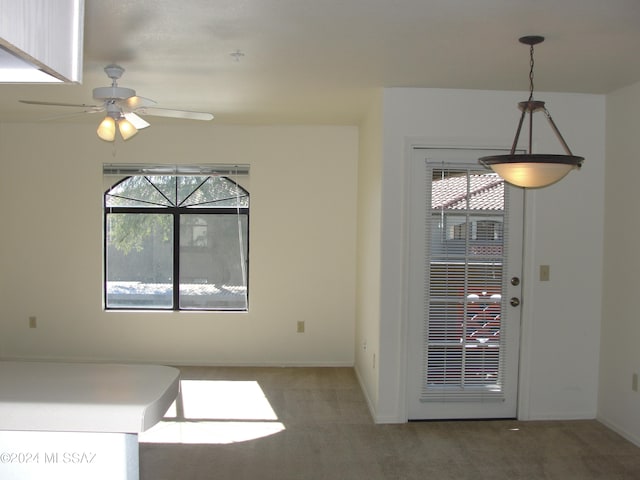 unfurnished dining area featuring carpet flooring, ceiling fan, and plenty of natural light