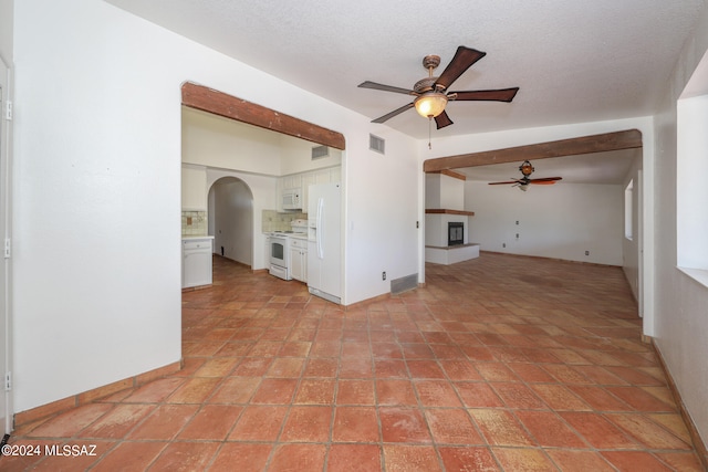 unfurnished living room featuring ceiling fan and a textured ceiling