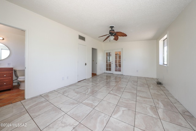 unfurnished room featuring ceiling fan, french doors, light tile patterned floors, and a textured ceiling