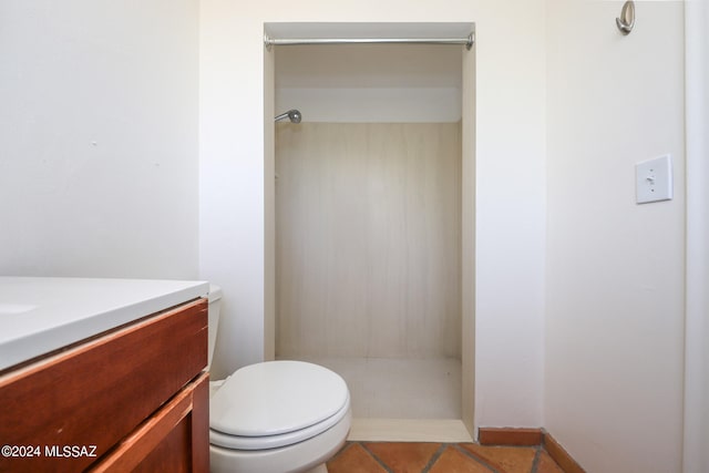 bathroom featuring tile patterned flooring, vanity, toilet, and walk in shower