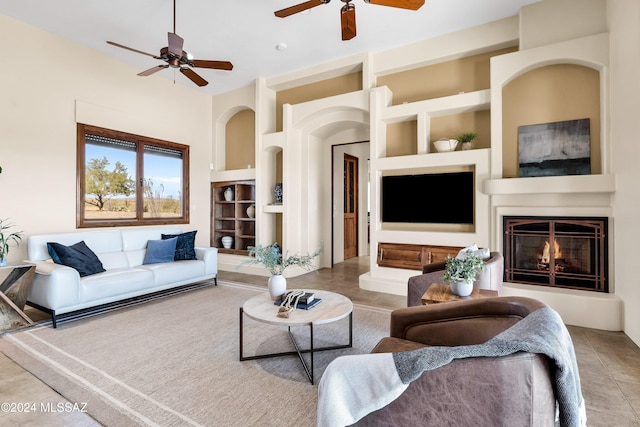 living room with built in features, tile patterned flooring, a large fireplace, and ceiling fan