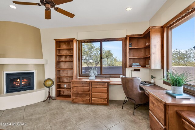 home office featuring light tile patterned floors, plenty of natural light, a fireplace, and built in desk