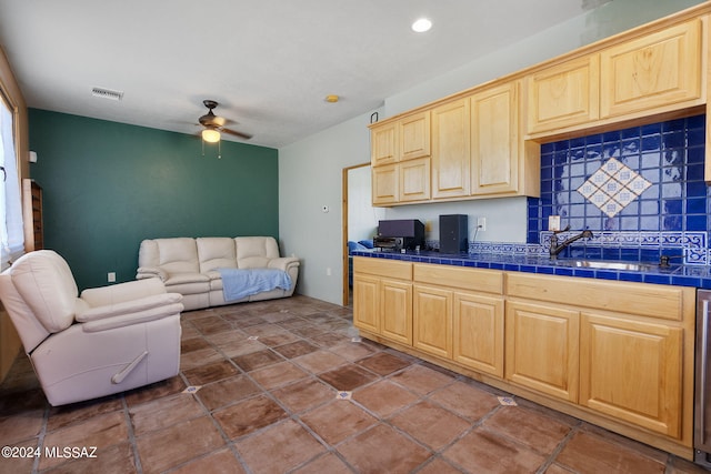 kitchen featuring tile counters, visible vents, decorative backsplash, light brown cabinetry, and open floor plan