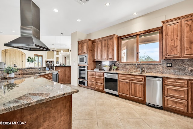 kitchen featuring brown cabinetry, island range hood, stainless steel appliances, and a sink