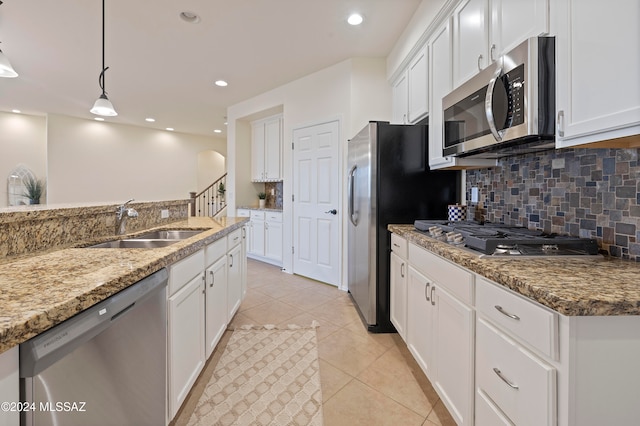 kitchen with white cabinets, appliances with stainless steel finishes, decorative light fixtures, and light stone countertops