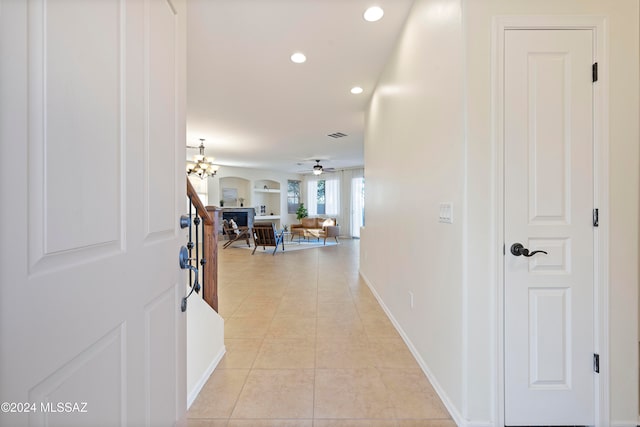 hall with light tile patterned flooring and a chandelier