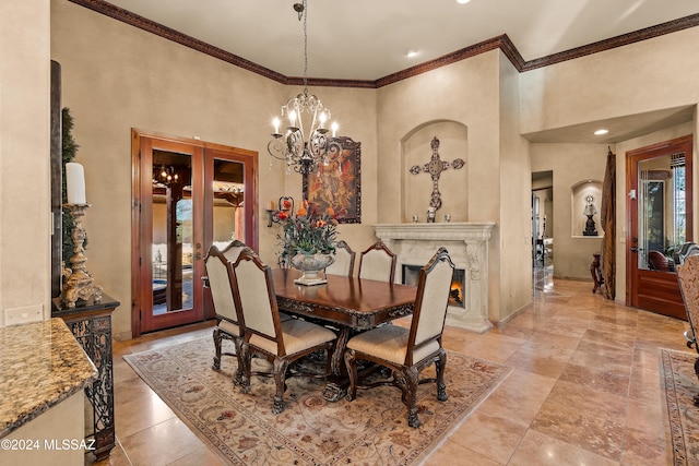 dining space featuring a fireplace, a towering ceiling, an inviting chandelier, and crown molding