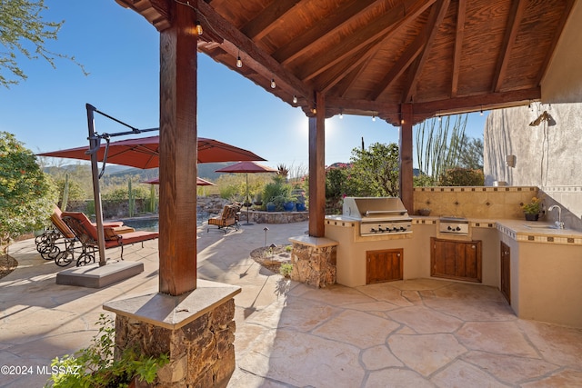 view of patio / terrace featuring an outdoor kitchen, a grill, sink, and a gazebo