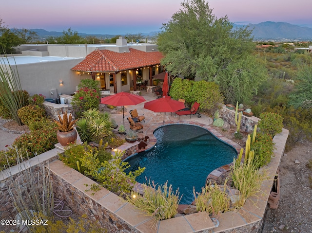 pool at dusk with a mountain view and a patio