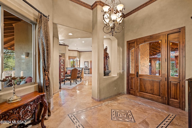 foyer entrance with a chandelier, ornamental molding, and a towering ceiling