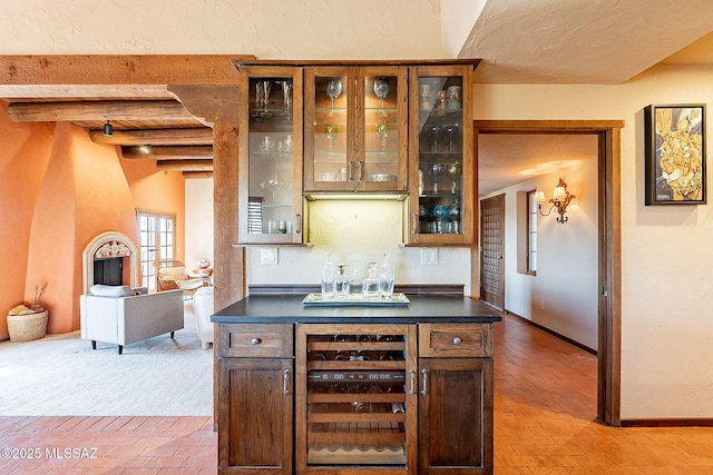 bar featuring beam ceiling, dark brown cabinets, light colored carpet, and beverage cooler