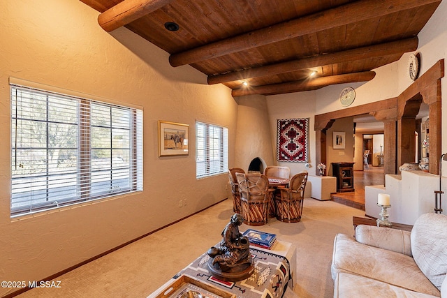 living room featuring beamed ceiling, light carpet, and wood ceiling