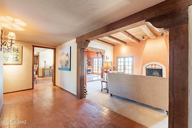 corridor featuring french doors, beamed ceiling, and a textured ceiling