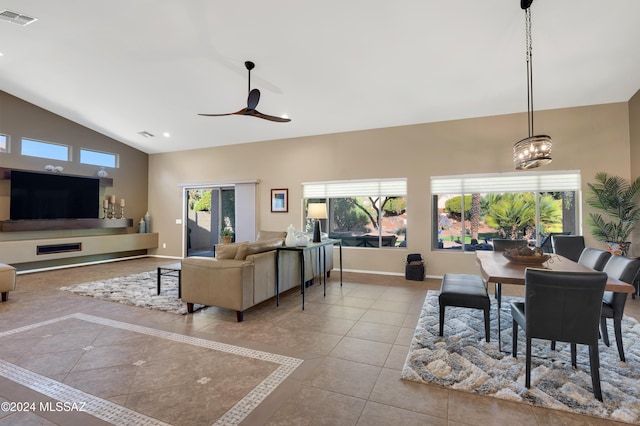 tiled living room with lofted ceiling and ceiling fan with notable chandelier