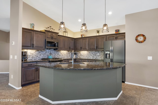 kitchen with pendant lighting, appliances with stainless steel finishes, an island with sink, sink, and dark brown cabinets