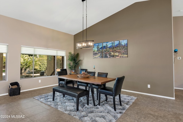 tiled dining area featuring high vaulted ceiling and an inviting chandelier